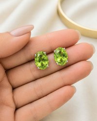 Bright lime green oval crystal earrings shown on hand to display size and sparkle in natural lighting