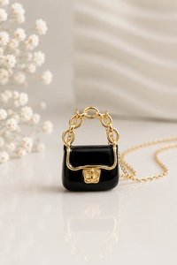 Mini handbag charm necklace displayed on an elegant surface.