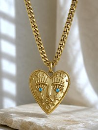 Statement gold heart face pendant necklace featuring aquamarine crystals on a thick stainless steel chain.