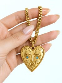 Chunky gold stainless steel heart face necklace with aquamarine crystal eyes on a thick curb chain.