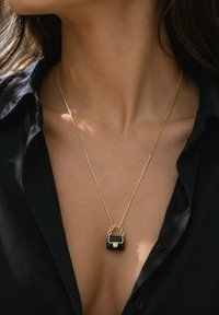 Fashion-inspired mini purse pendant necklace shown on a woman's neck.