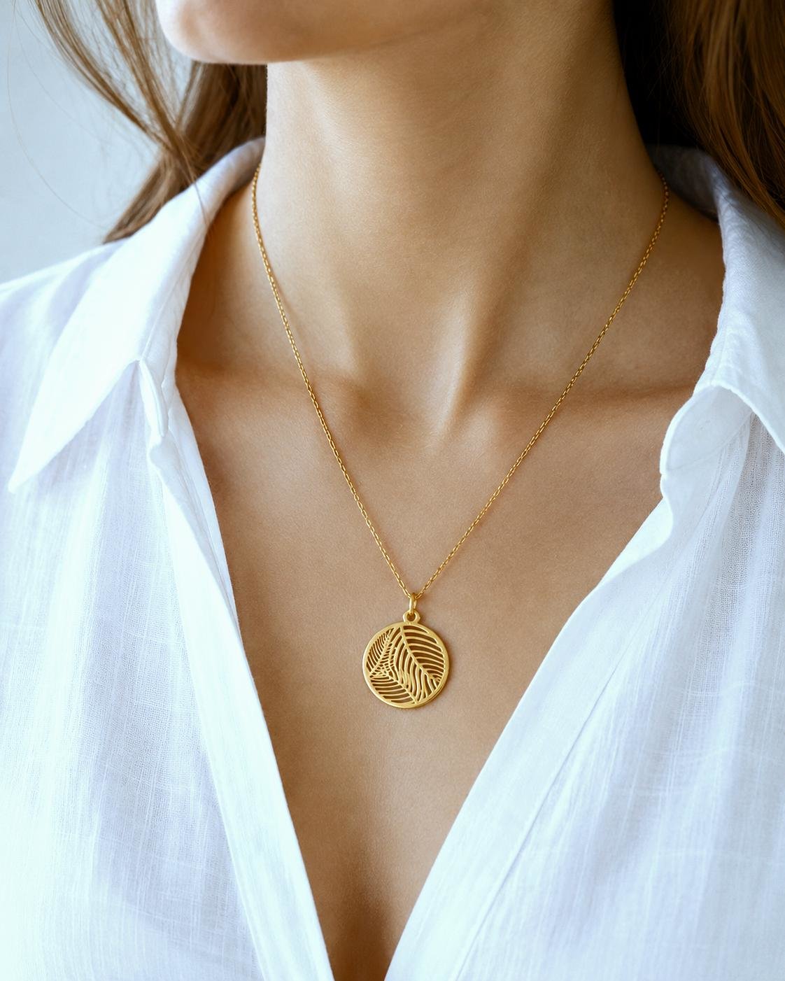 Minimal gold tropical leaf necklace with delicate chain on elegant model
