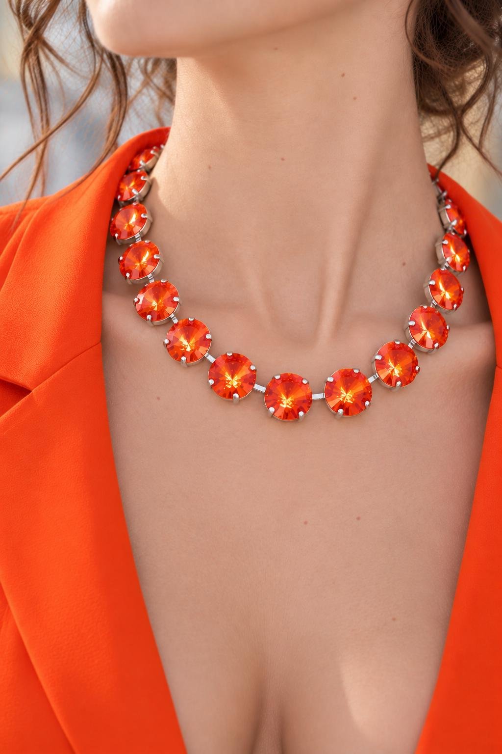 Woman wearing a double layer Swarovski orange crystal necklace with a bright orange open blazer. Bold Modern Jewelry