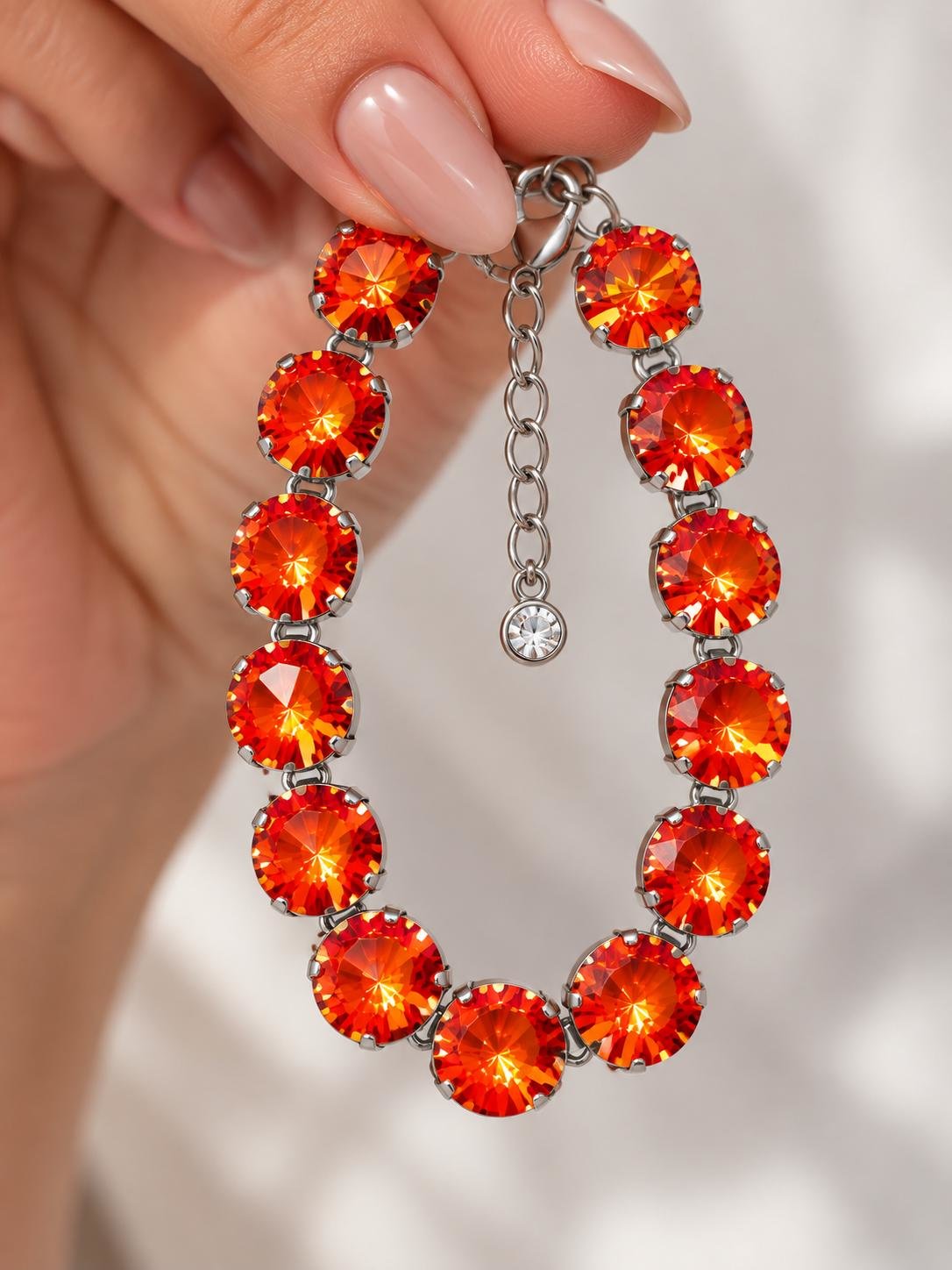 Close-up of sparkling Swarovski Orange Ignite Rivoli crystals showing the faceted 12mm stones and silver prong cup chain setting