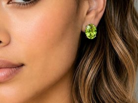 Silver plated oval green crystal stud earrings worn on ear with elegant everyday styling and soft makeup look.